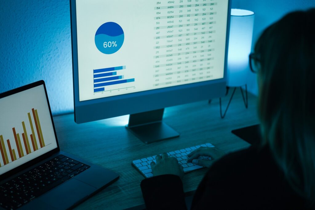 Young woman analyzing data charts for marketing financial reports - Focus on left computer screen